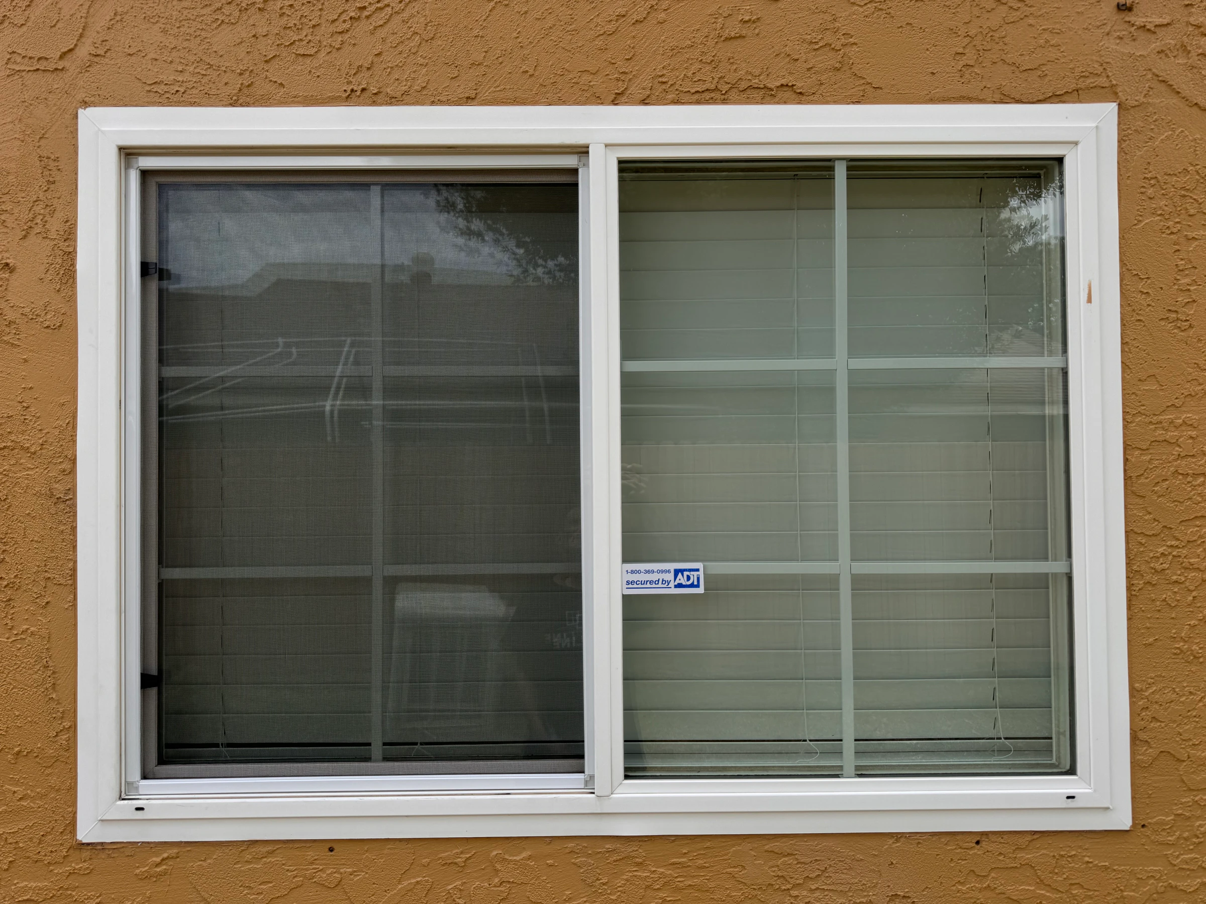 White sliding window after a fitted black window screen was installed